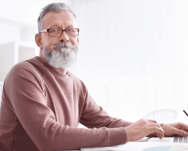 man with reading glasses with beard at desk