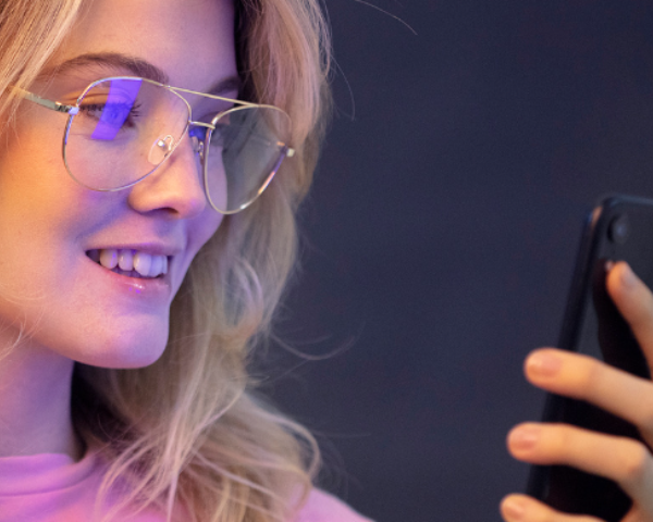 girl looking at phone screen wearing blue light blocking lenses
