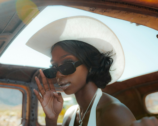 woman wearing a white cowgirl hat and rectangular sunglasses