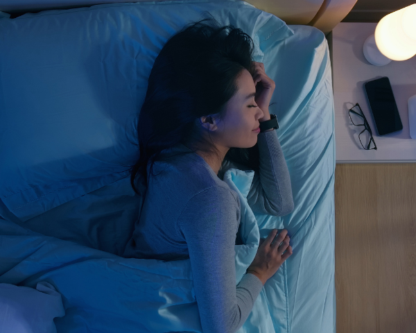 woman asleep in bed with blue light glowing