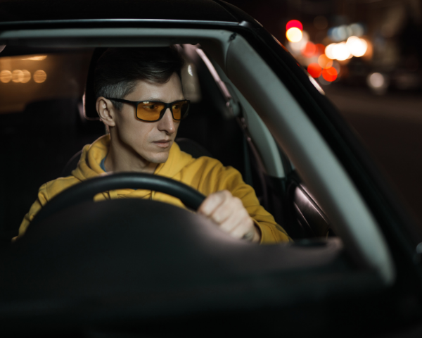man driving a car wearing driving glasses