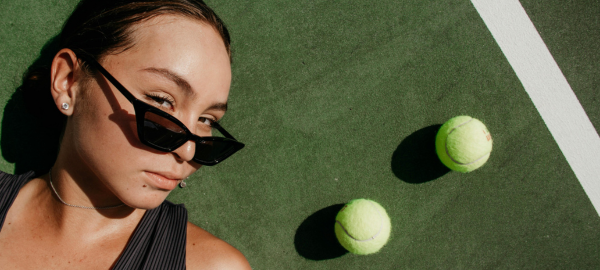 woman on a tennis court wearing sunglasses
