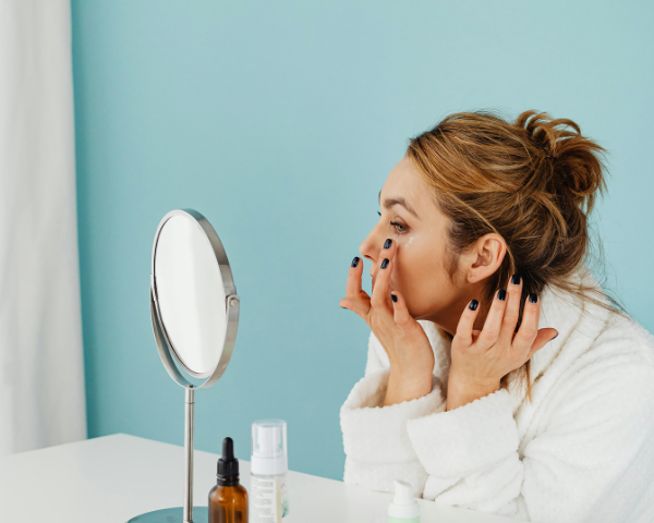 woman using magnifying mirror to apply makeup
