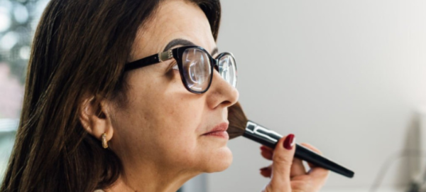 woman wearing glasses applying makeup