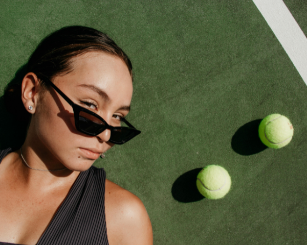 woman on tennis court wearing sunglasses