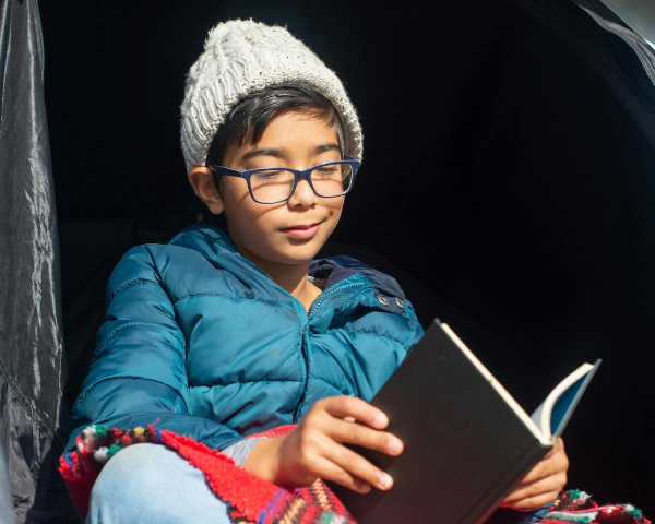 young boy wearing glasses and reading a book