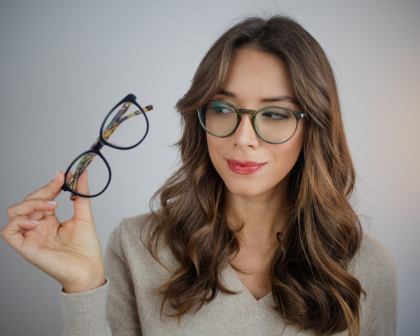 Woman holding a pair of glasses and looking at them