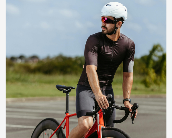 Man wearing cycling sunglasses standing over a bike