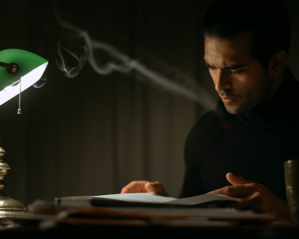 Man sitting on a desk reading with dim lighting
