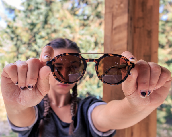 woman holding animal print sunglasses