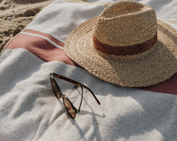 Sunglasses and a hat on a beach towel