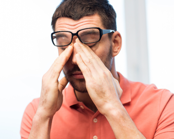 Man rubbing eyes under eyeglasses