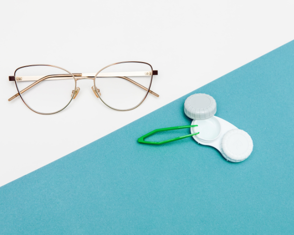 Pair of glasses on one side with a white background, a pair of contact lens case on the right side with a blue background