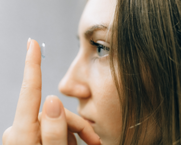 Woman holding a contact lens close to her eye