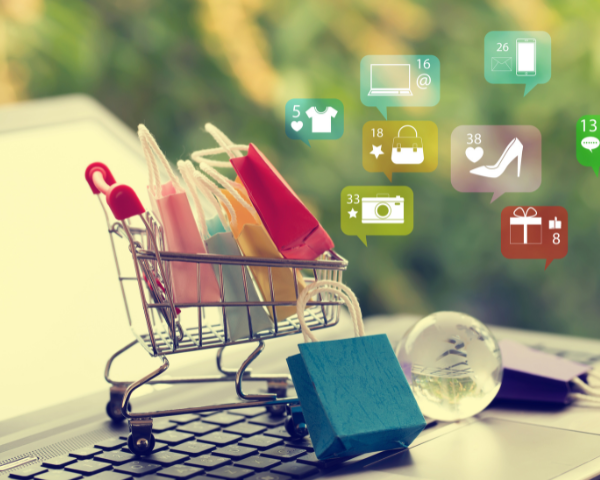 Small shopping cart filled with shopping bags on top of a keyboard