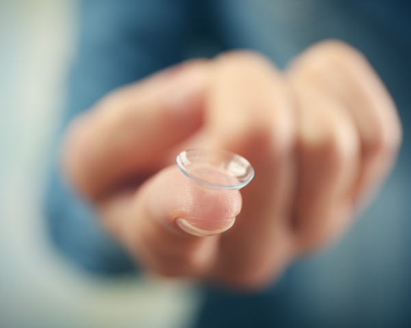 finger holding out a contact lens