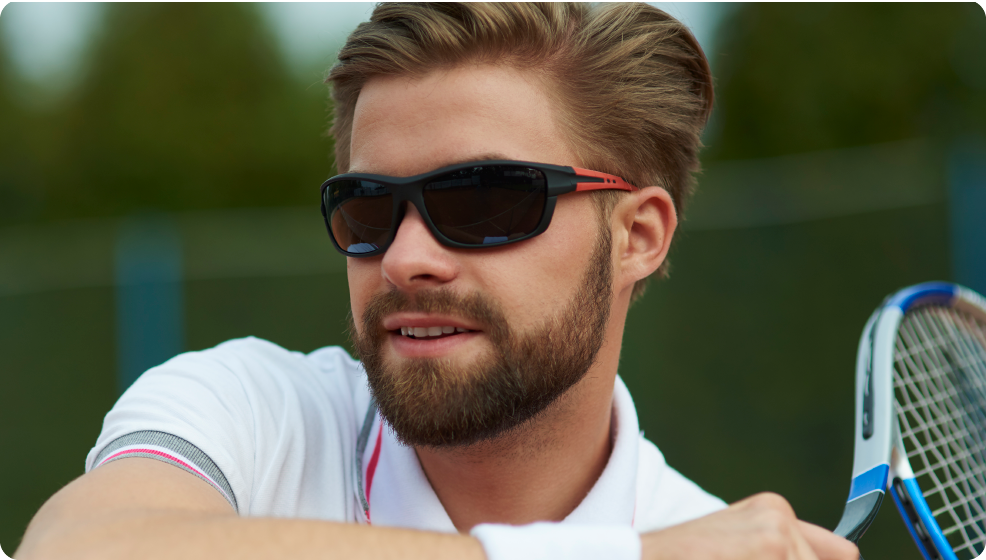 Man playing tennis wearing sunglasses