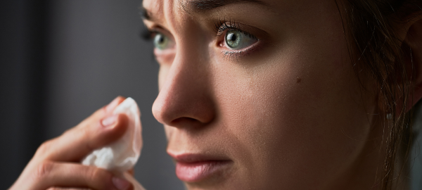 woman with watery eyes and tissue in hand