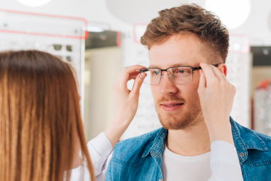 optician fitting glasses on a guy