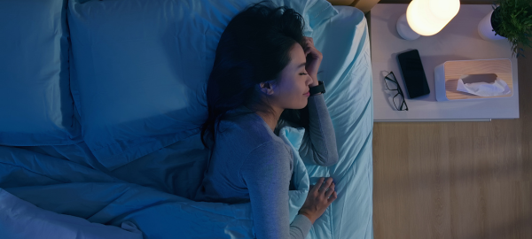 woman laying in bed with blue light glowing on her face