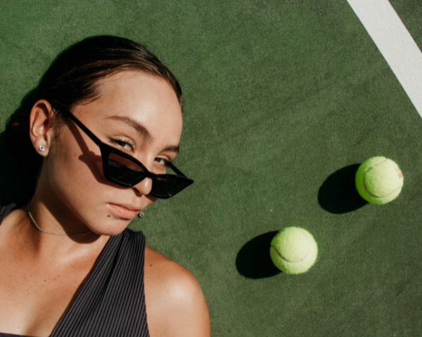 woman on a tennis court wearing sunglasses