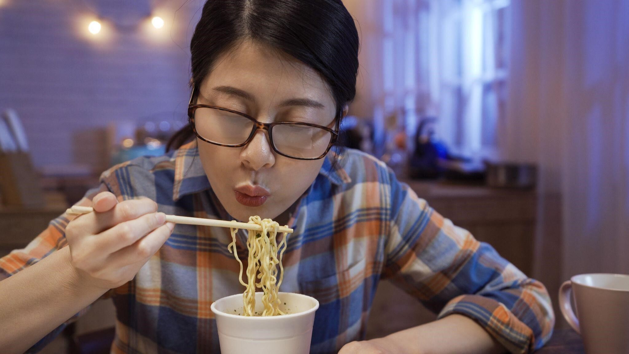 A girl eatinghot noddles as her glasses fog up