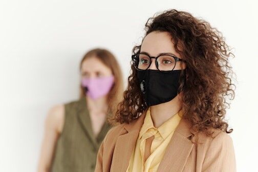 Two women wearing a mask and one wearing also glasses