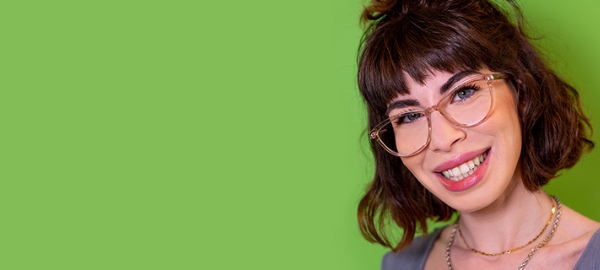 Simling woman wearing clear glasses frames with green background