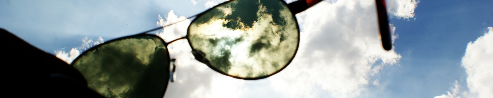 Person holding up sunglasses to the sky