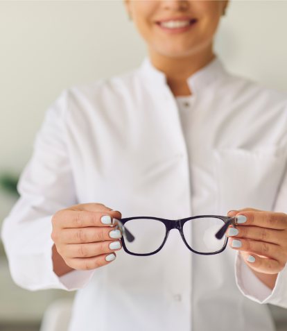 Optician holding black pair of glasses out in front of them