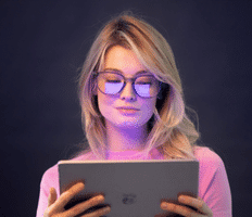 blonde woman using ipad wearing blue light glasses