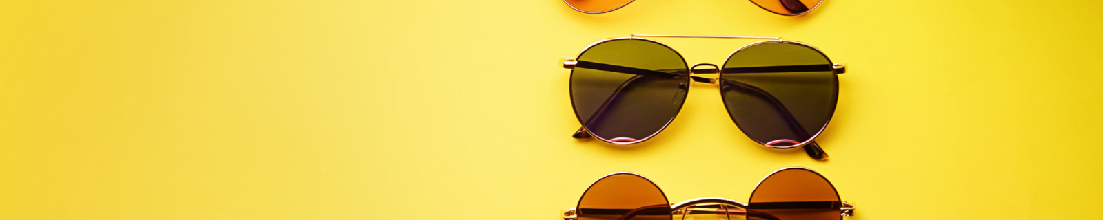 Thee pairs of sunglasses led flat on a yellow background