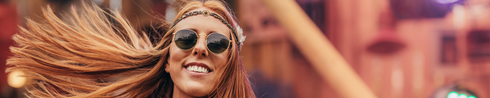 Red haired woman smiling with black sunglasses and a headband on