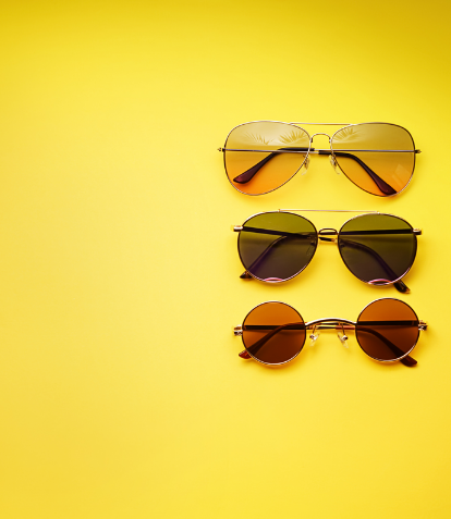 Three pairs of sunglasses led flat on a yellow background