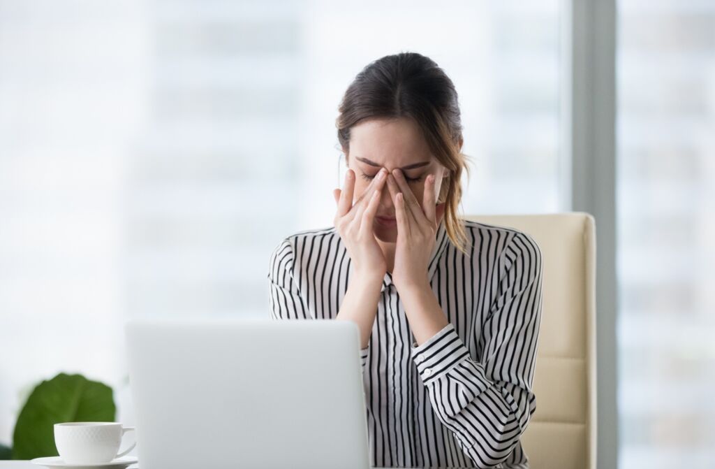 Woman sat at a computer rubbing her eyes