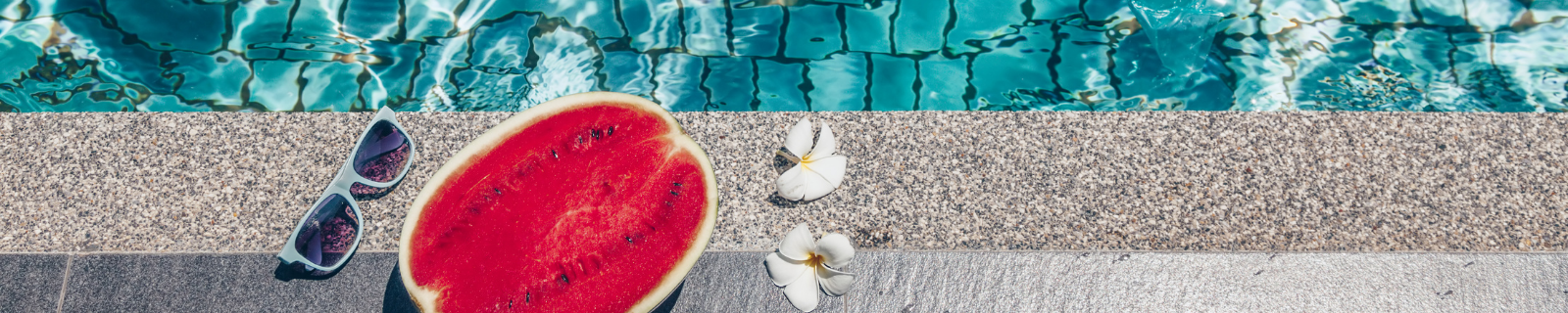 Poolside with a pair of sunglasses, some white flowers and half a watermelon