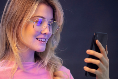 girl wearing blue light glasses holding phone