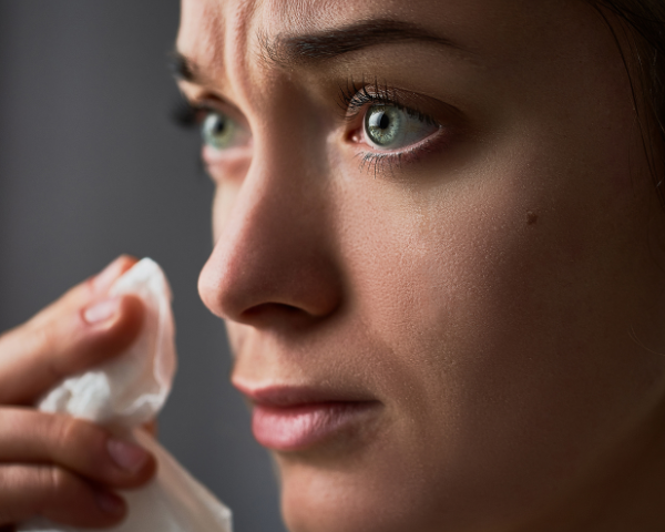 Woman with watery eyes holding a tissues