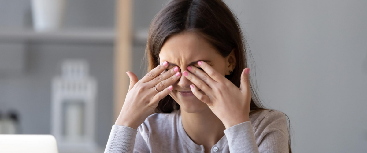 woman sitting at her desk, rubbing her eyes from eye irritation