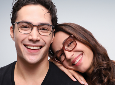 a male and a a female model, smiling and wearing glasses