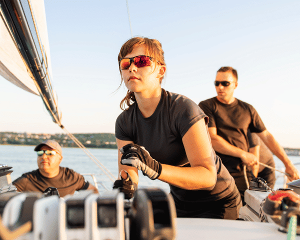 group of athletes on boat sailing wearing sugnlasses