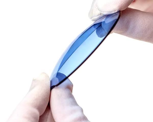 gloved hands holding blue tinted lens