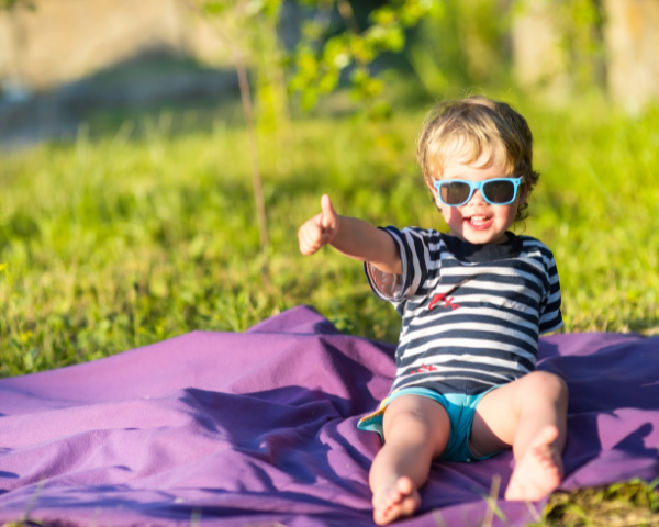 Kid wearing sunglasses sitting in the sun