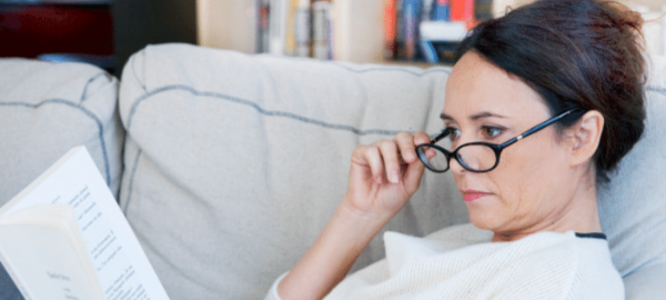 woman on couch reading wearing reading glasses