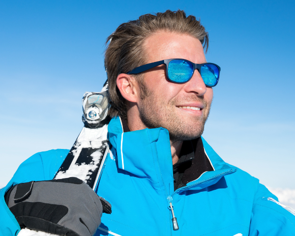 male athlete wearing polarised lenses with skiis on shoulder