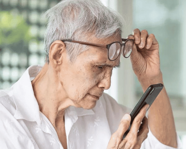 elderly lady with myopia putting on glasses to read phone screen