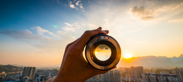 hand holding a lens against a sunset